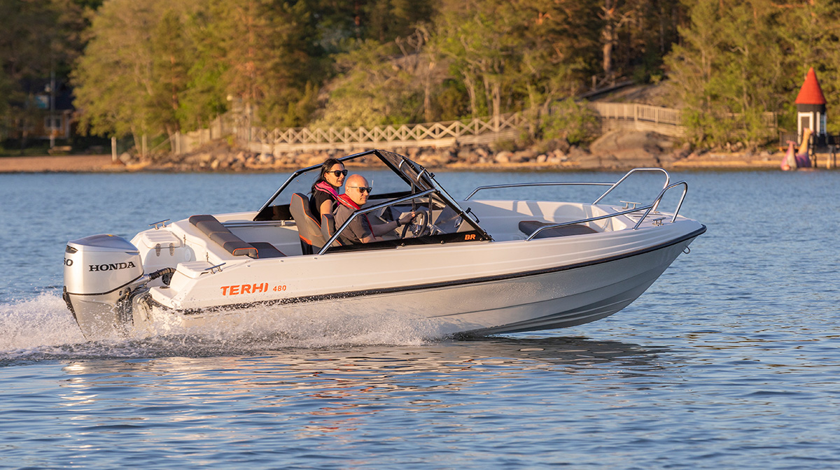Pariskunta ajaa Terhi 480 BR -moottoriveneellä ilta-auringossa.